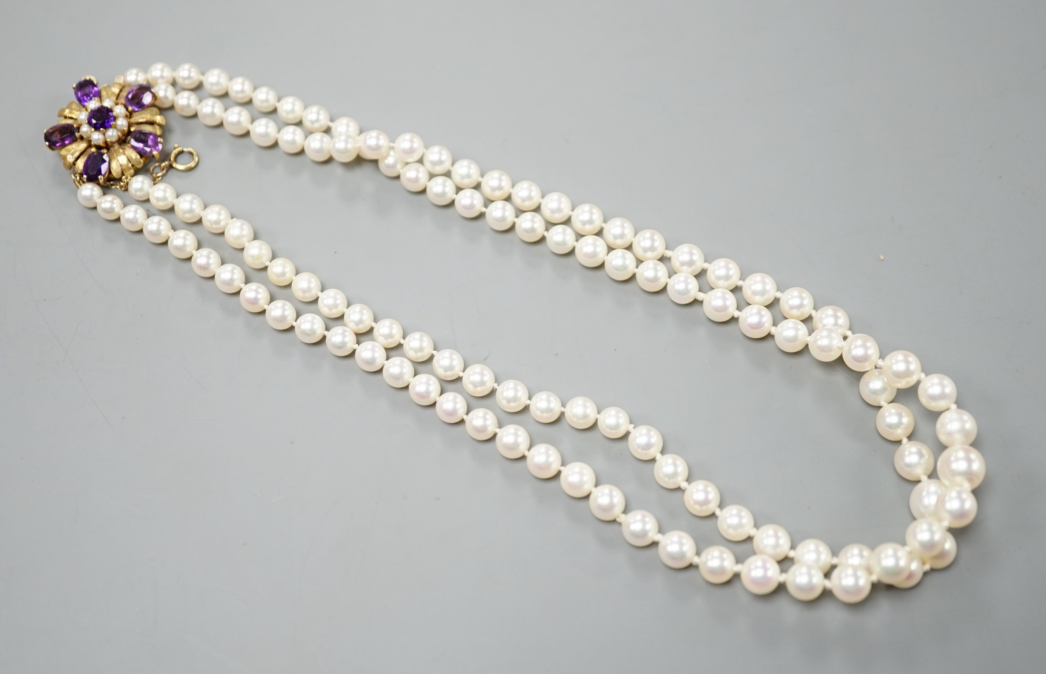A modern double strand graduated cultured pearl necklace, with amethyst and cultured pearl cluster set 9ct clasp, 42cm.